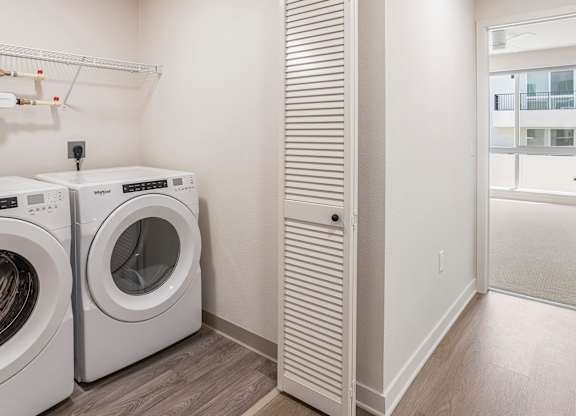 A laundry room with a washer and dryer and a tall white closet.
