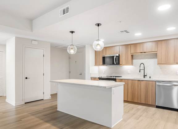 A modern kitchen with a white island and wooden cabinets.