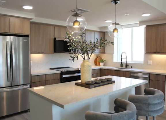 Kitchen island with globe pendants and gray chairs at Garden at 3Roots Apartments, California, 92126