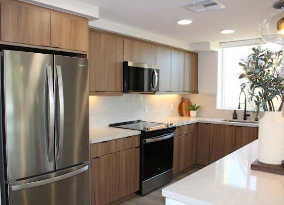 Kitchen with wood cabinets and stainless steel appliances at Garden at 3Roots Apartments, San Diego, CA 92126