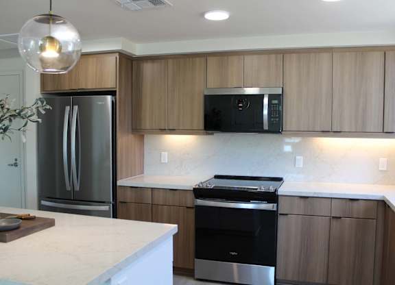 Kitchen with black appliances and marble backsplash at Garden at 3Roots Apartments, San Diego, CA