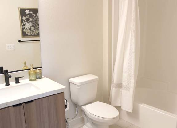 Bathroom with white tub and shower curtain at Garden at 3Roots Apartments, San Diego