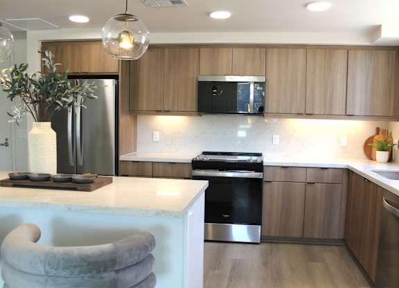 Kitchen with wood cabinetry and white marble counters at Garden at 3Roots Apartments, California, 92126