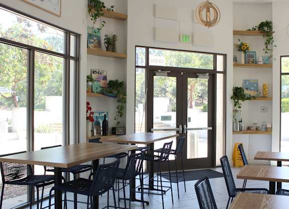 Cafe seating area with wooden tables and plants at Torrey Gardens Apartments, San Diego, 92130