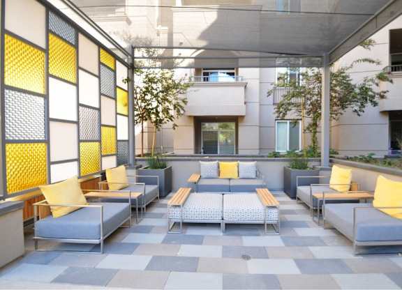 Outdoor courtyard lounge with modern seating and yellow accents at 360 Luxury Apartments, California