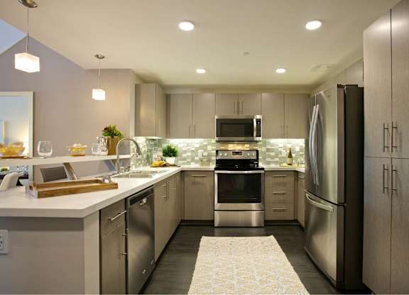 Modern kitchen with stainless steel appliances and white countertops at 360 Luxury Apartments, San Diego, CA