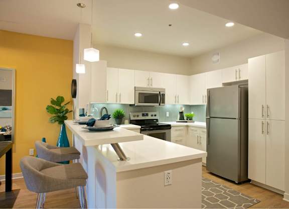 Modern kitchen with breakfast bar and pendant lighting at 360 Luxury Apartments, San Diego, 92122