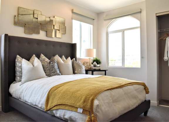 Bedroom with tufted headboard and gold throw blanket at 360 Luxury Apartments, California, 92122