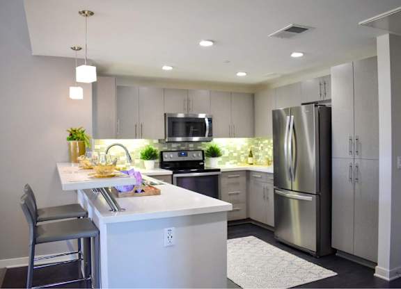 Kitchen island with bar seating and pendant lights at 360 Luxury Apartments, San Diego, CA 92122