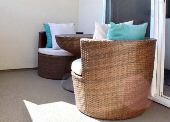 Private balcony with wicker barrel chairs and pillows at 360 Luxury Apartments, San Diego