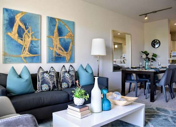Living room with blue artwork and peacock throw pillows at 360 Luxury Apartments, San Diego, CA