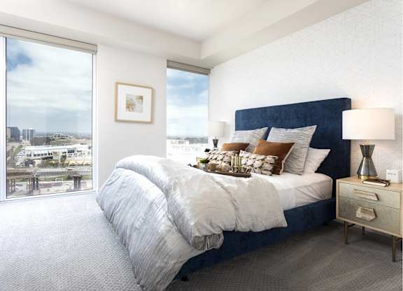 Bright bedroom with navy upholstered bed and city views at LUX by Garden* Apartments, California, 92122