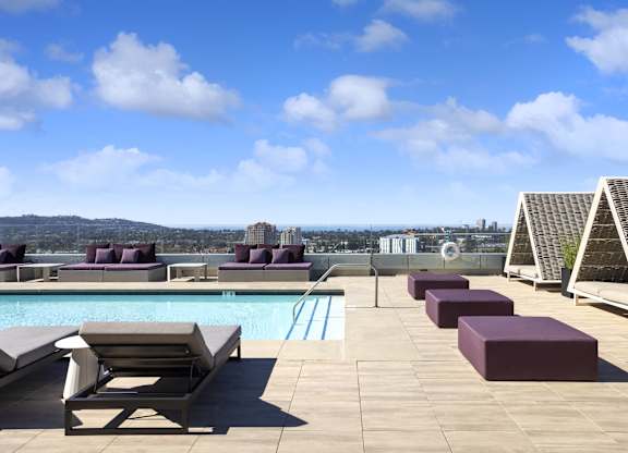 Rooftop pool deck with cabanas and purple loungers at LUX by Garden* Apartments, San Diego, CA 92122
