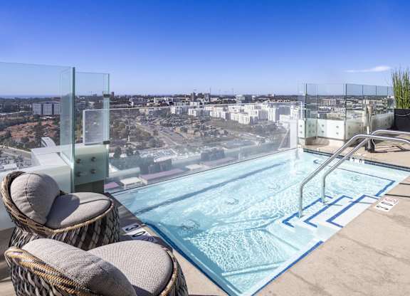 Rooftop spa with glass railing and city views at LUX by Garden* Apartments, California
