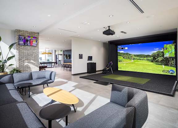 Indoor golf simulator lounge with putting green at LUX by Garden* Apartments, San Diego, CA