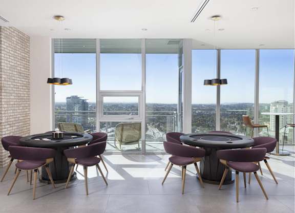 Game room with poker tables and panoramic windows at LUX by Garden* Apartments, California
