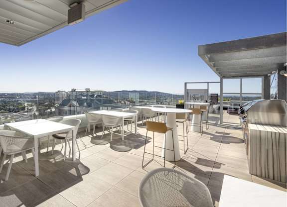 Rooftop dining terrace with outdoor kitchen and city views at LUX by Garden* Apartments, California