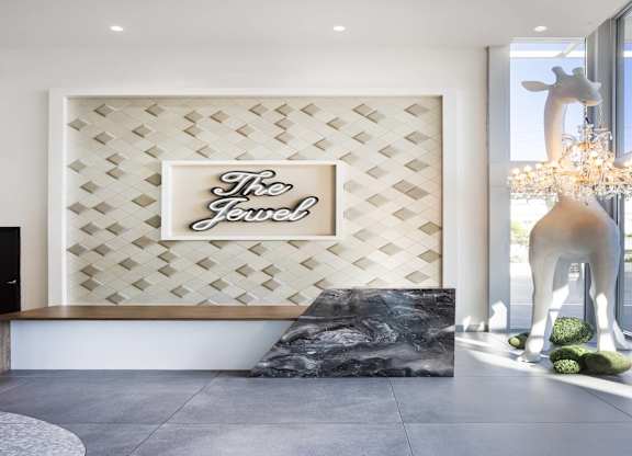 Reception desk with decorative wall and giraffe sculpture at LUX by Garden* Apartments, San Diego, CA 92122