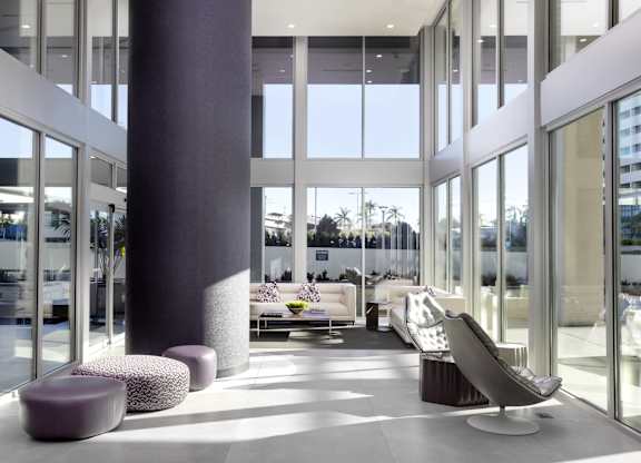 Modern lobby with double height windows and seating at LUX by Garden* Apartments, California