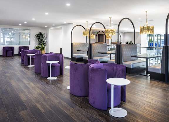 Modern lounge with booth seating and purple chairs at LUX by Garden* Apartments, San Diego, CA