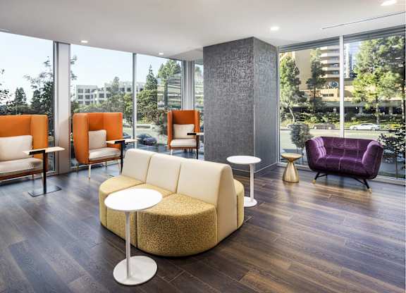 Modern lounge with orange privacy chairs and curved sofa at LUX by Garden* Apartments, San Diego