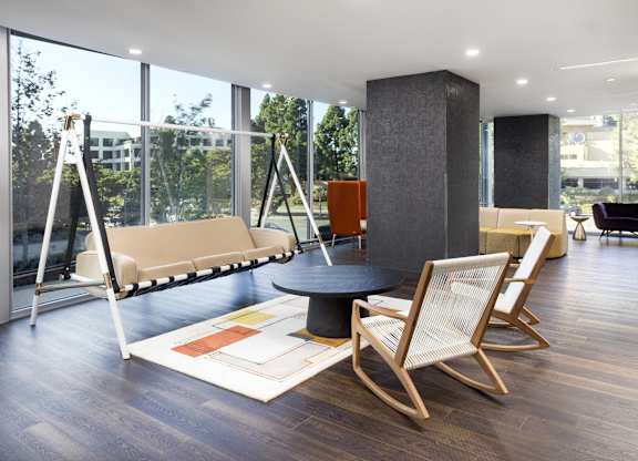 Lounge area with swing seating and floor to ceiling windows at LUX by Garden* Apartments, California