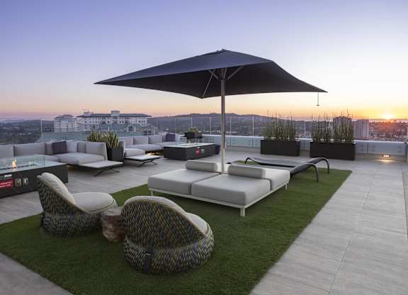 Rooftop lounge with umbrella seating and sunset views at LUX by Garden* Apartments, California