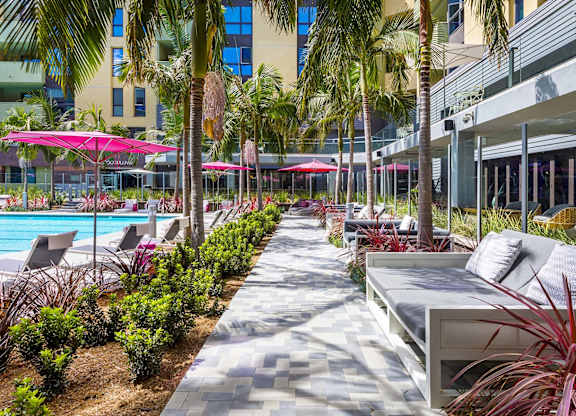 Landscaped poolside walkway with lounge seating at Metropolis Apartments, IRVINE, California