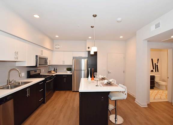 Modern kitchen with island seating and pendant lighting at Metropolis Apartments, IRVINE, CA 92614