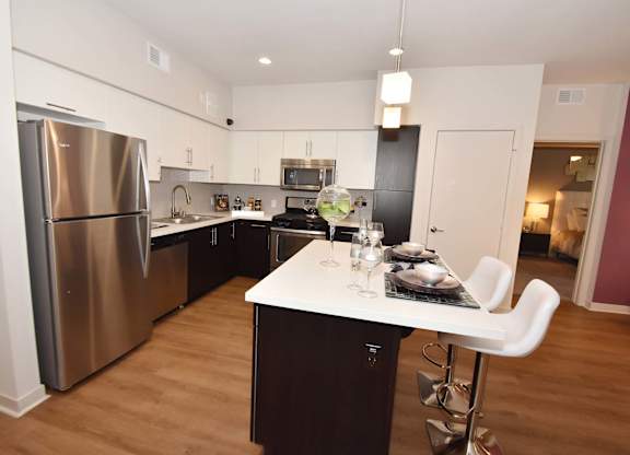 A modern kitchen with a dining table set at Metropolis Apartments, IRVINE, CA 92614