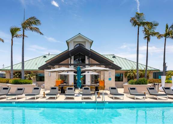 A pool area with a building and palm trees. at Towers at Costa Verde Apartments, San Diego, CA, 92122