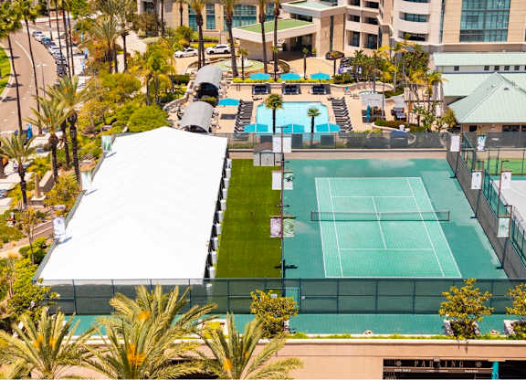 Tennis court surrounded by palm trees and buildings. at Towers at Costa Verde Apartments, San Diego, 92122