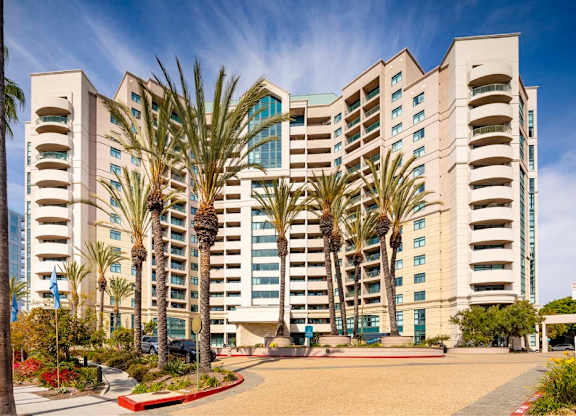A large building with palm trees in front of it. at Towers at Costa Verde Apartments, San Diego, California