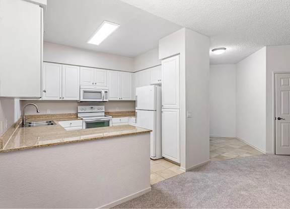 A kitchen with white cabinets and appliances. at Towers at Costa Verde Apartments, San Diego, California