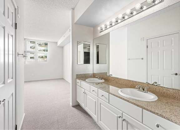 A bathroom with a vanity and a mirror with lights above it. at Towers at Costa Verde Apartments, California, 92122