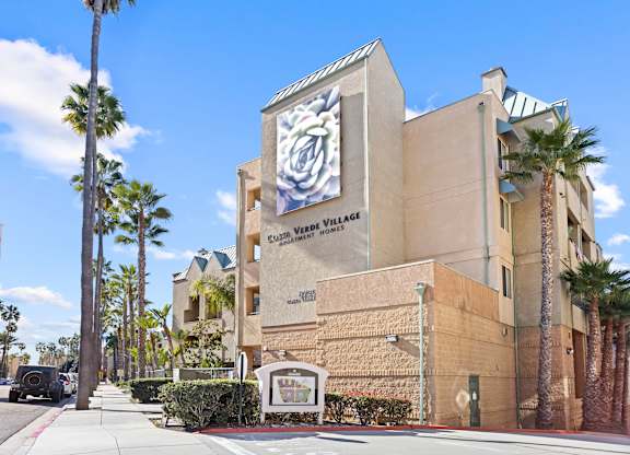 Apartment building exterior with palm trees at Costa Verde Village Apartments, San Diego, CA
