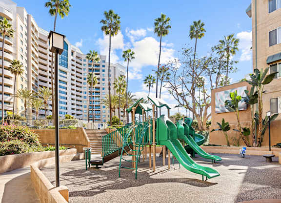 Community playground with green slides and palm trees at Costa Verde Village Apartments, San Diego, 92122