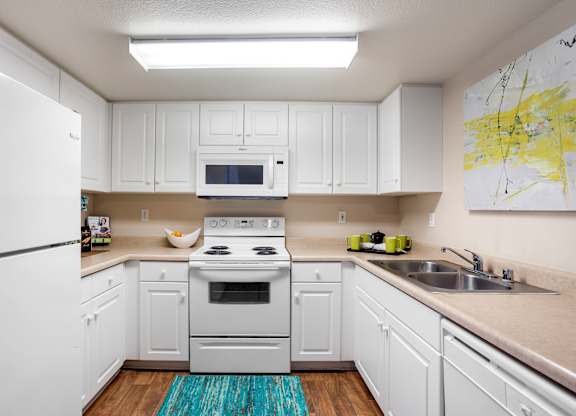 White kitchen with electric range and microwave at Costa Verde Village Apartments, California, 92122