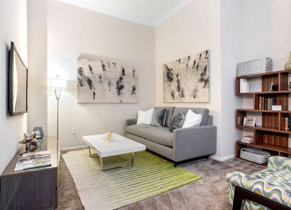 Living room with gray sofa and bookshelf at Costa Verde Village Apartments, San Diego