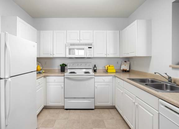 White kitchen with double sink and overhead microwave at Costa Verde Village Apartments, San Diego, 92122