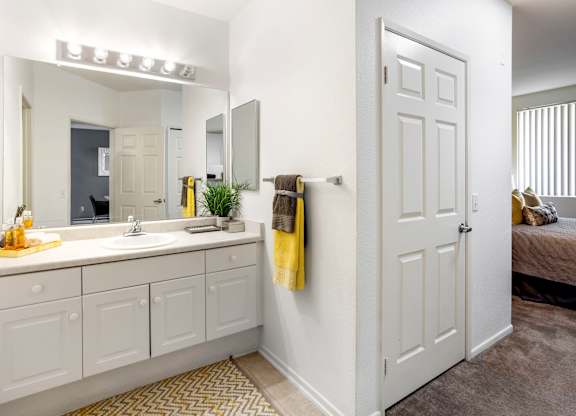 Bathroom with white vanity and yellow accents at Costa Verde Village Apartments, San Diego, California