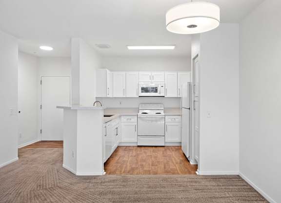White kitchen with white appliances and peninsula counter at Costa Verde Village Apartments, San Diego, CA 92122