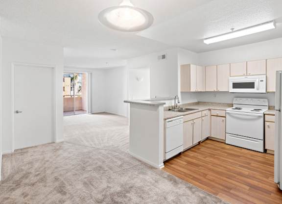Open kitchen with breakfast bar and carpeted living area at Costa Verde Village Apartments, California, 92122