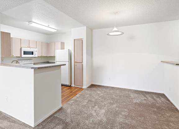 Open kitchen with breakfast bar and carpeted living space at Costa Verde Village Apartments, San Diego, CA 92122