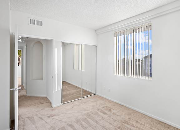 Empty bedroom with mirrored closet and vertical blinds at Costa Verde Village Apartments, San Diego, CA