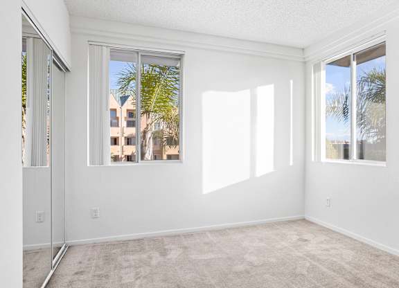 Bright empty bedroom with mirrored closet doors at Costa Verde Village Apartments, San Diego, California