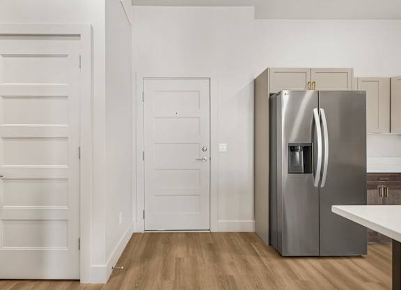A kitchen with a refrigerator, two doors, and a counter.