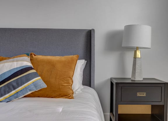 a bedroom with a bed and a nightstand with a lamp on it