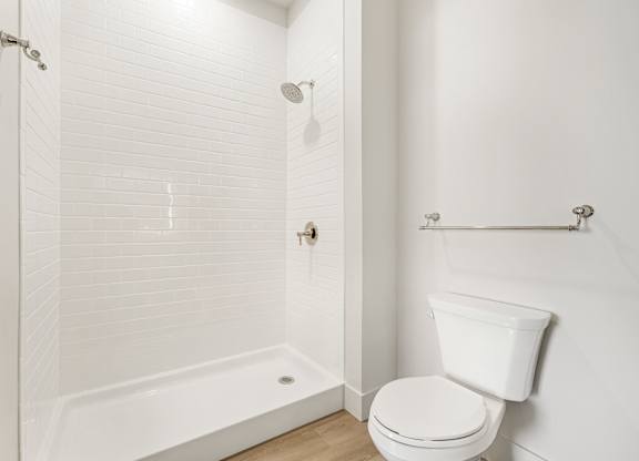 A white bathroom with a toilet and a walk-in shower.