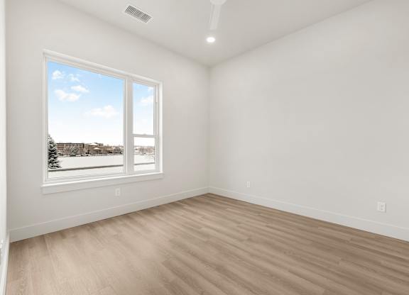 A room with a large window and wooden flooring.